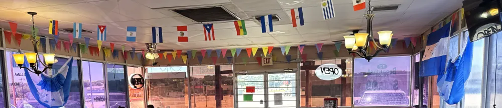 A line of Latin American national flags strung the length of the dining room ceiling, with papel picado between them and two Honduran flags hanging on the window wall.