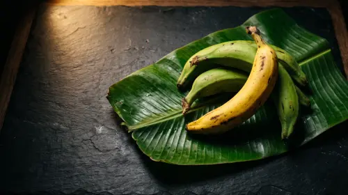 Green and ripe plantains on a banana leaf.